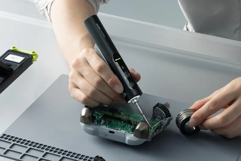 A person using Hoto’s soldering iron to repair a video game controller.
