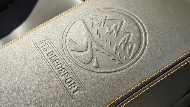 Embossed logo and text "GT3 BERGSPORT" on textured leather surface with orange stitching.
