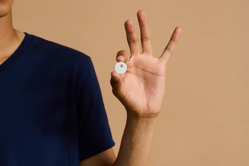 A person holding an Abbott Libre Duo in their fingers