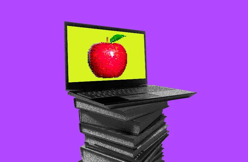 laptop with an apple on a stack of books