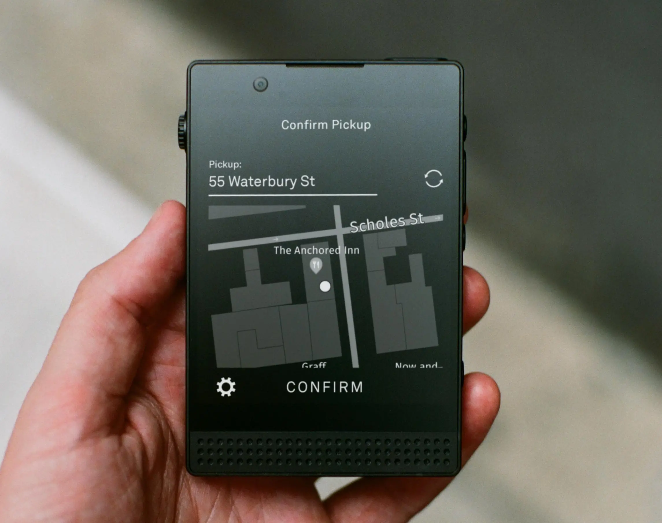 Light Phone III in hand showing a “confirm pickup” screen for Uber with an address and a map.