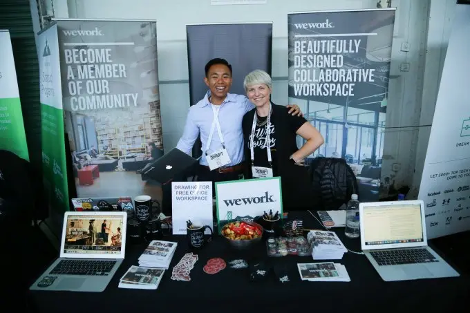 People working at the WeWork exhibit table at TechCrunch Disrupt NYC 2017