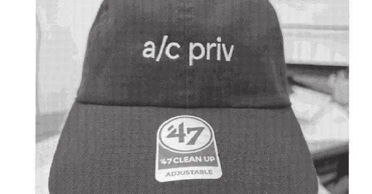 grayscale picture of a baseball cap with a/c priv across the front