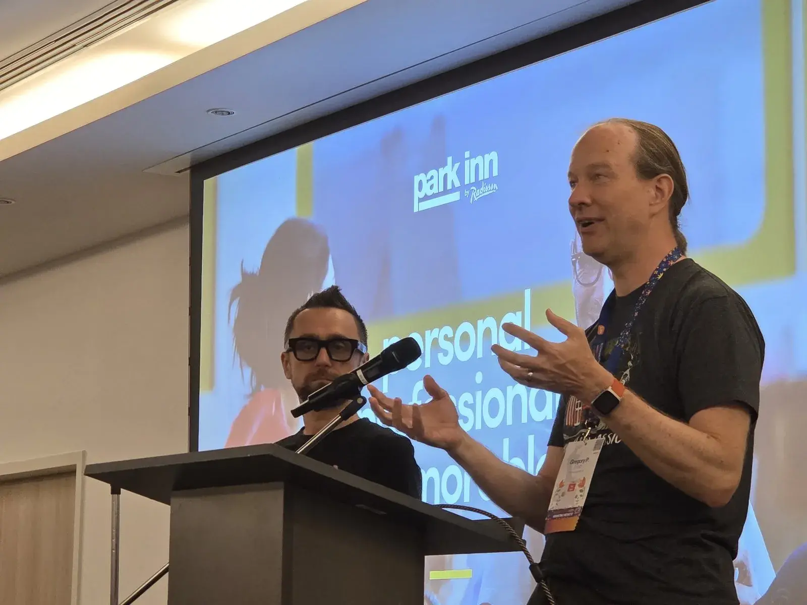 Gregory P. Smith speaking at the lectern with Łukasz Langa beside him