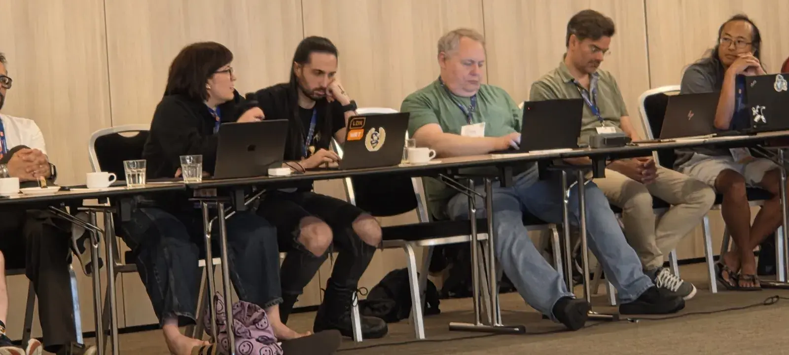 Savannah Ostrowski speaking from her seat at the table, with other attendees at laptops beside her