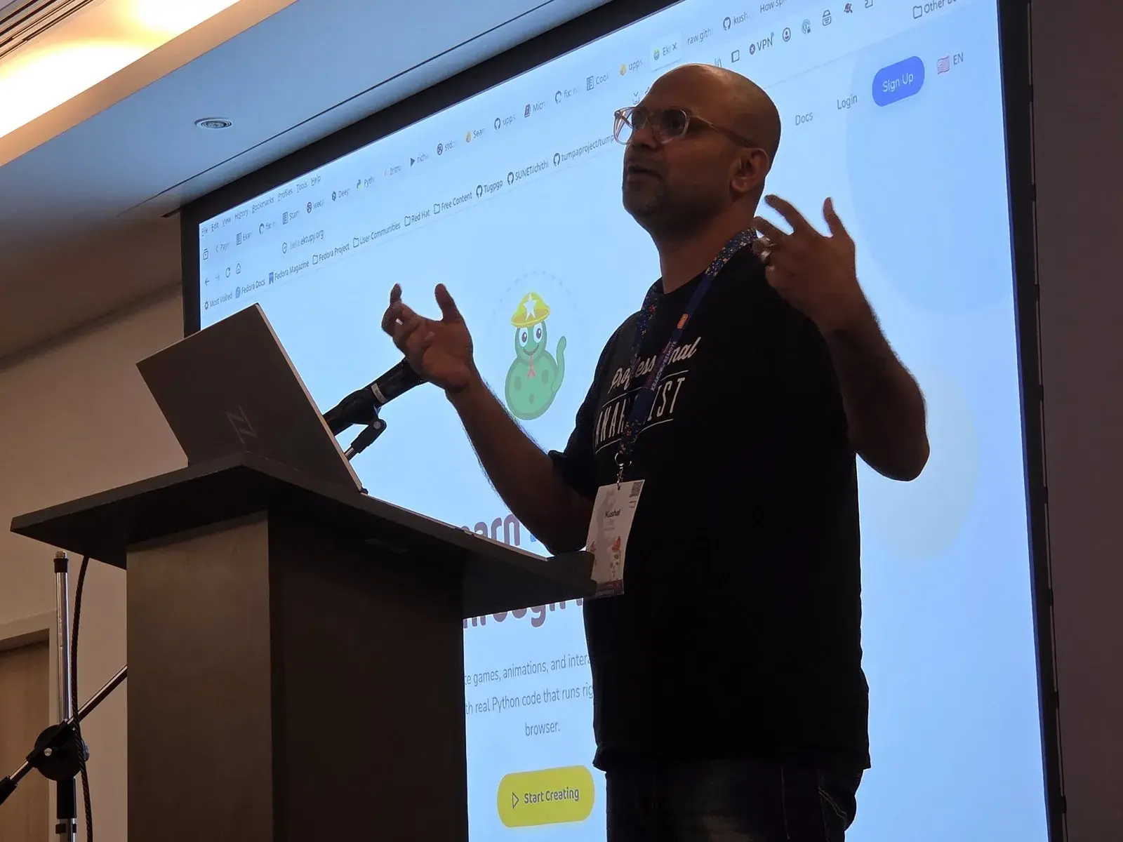 Kushal Das at the lectern, gesturing in front of the EktuPy website projected behind him