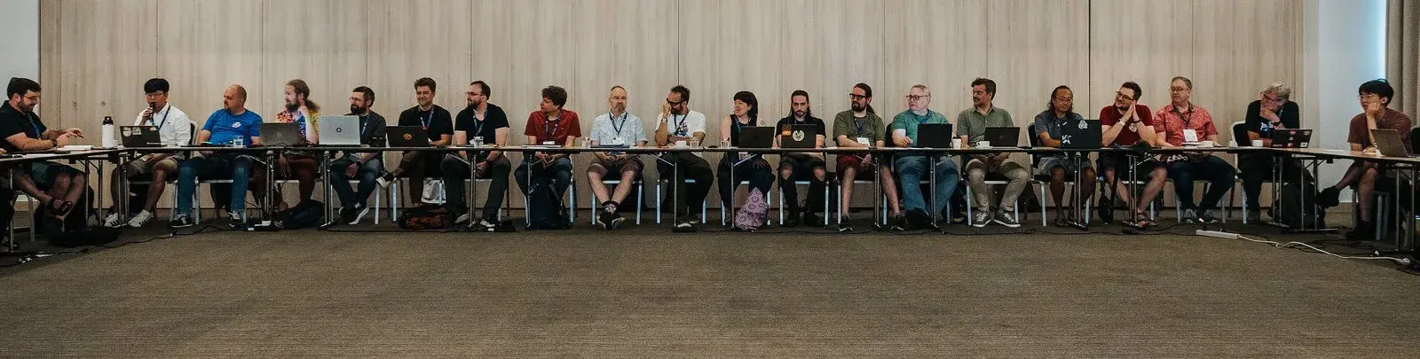 Donghee Na speaking into a microphone among Language Summit attendees seated along the U-shaped table