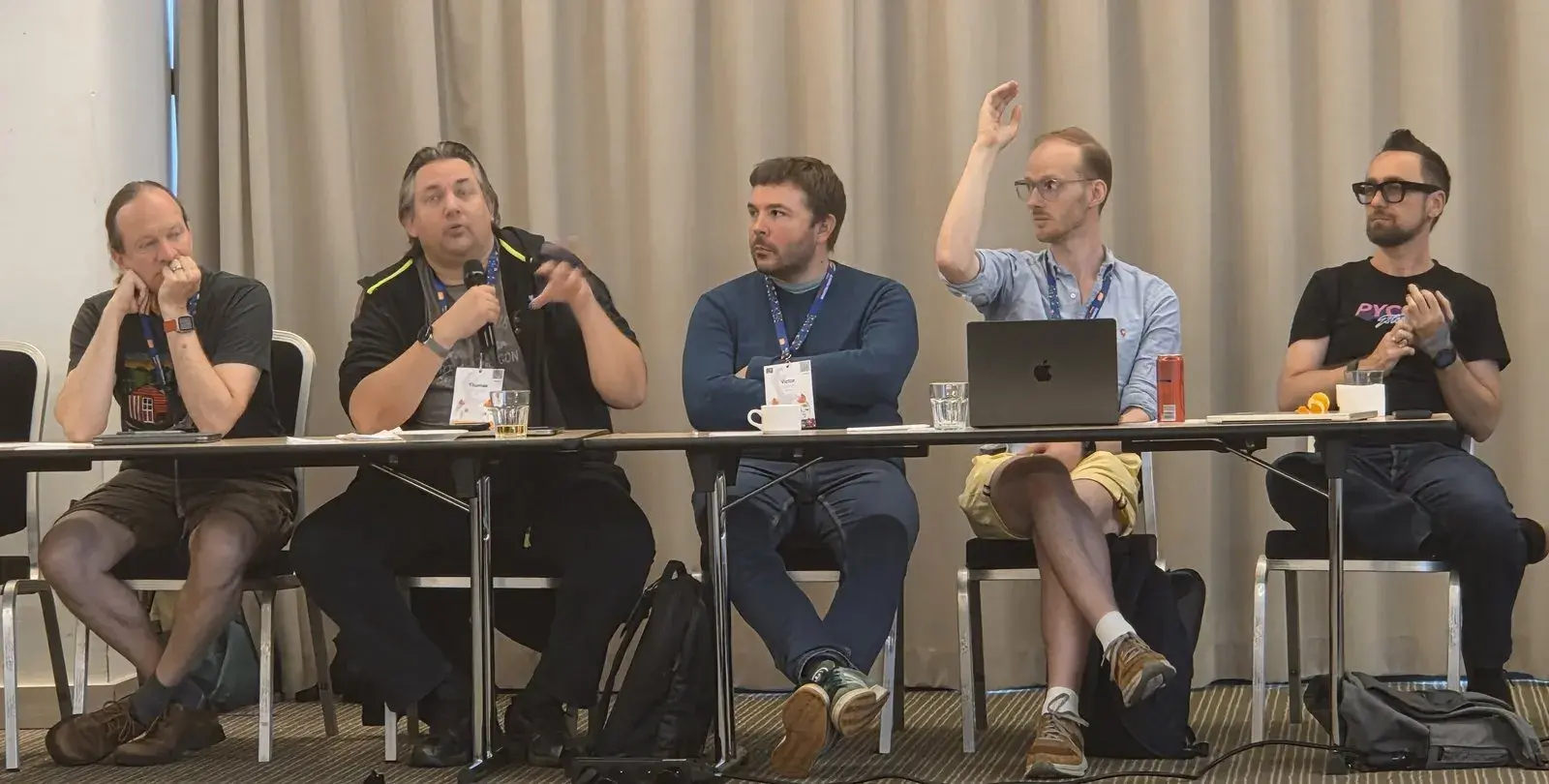 Thomas Wouters speaking into a microphone, seated in a row of attendees
