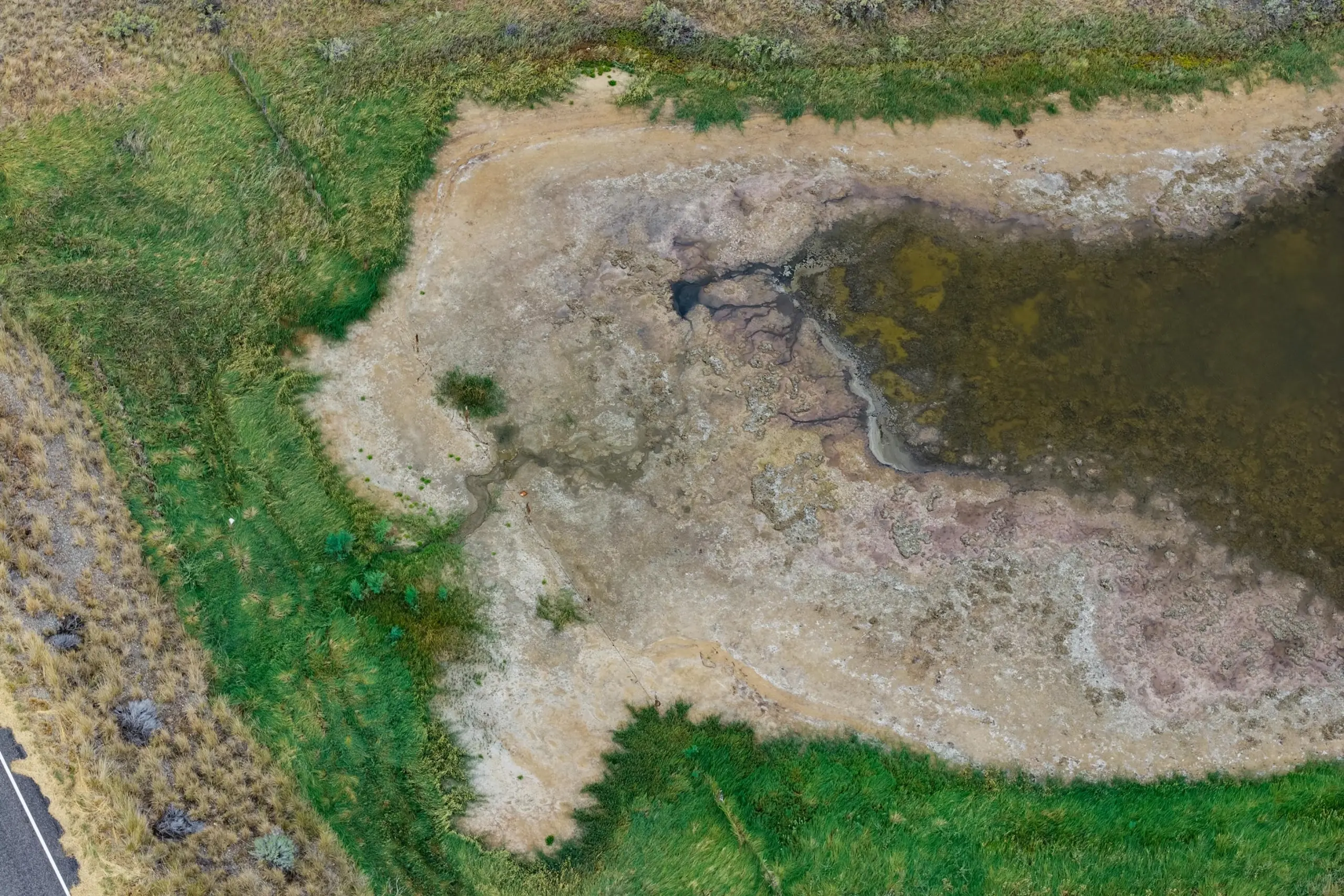 An aerial view of grass and mud next to a road.
