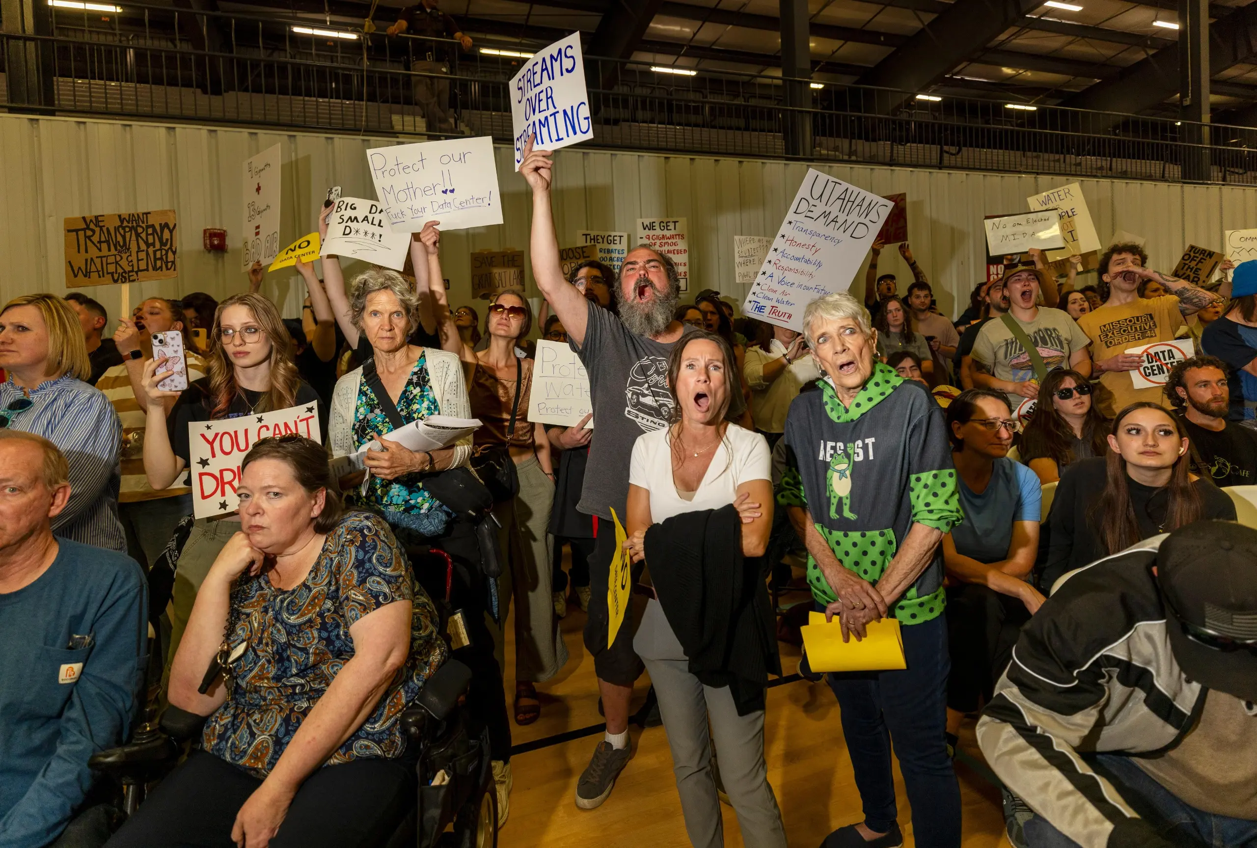 A crowd of people, holding signs, present at the Box Elder County Commission reacting angrily.