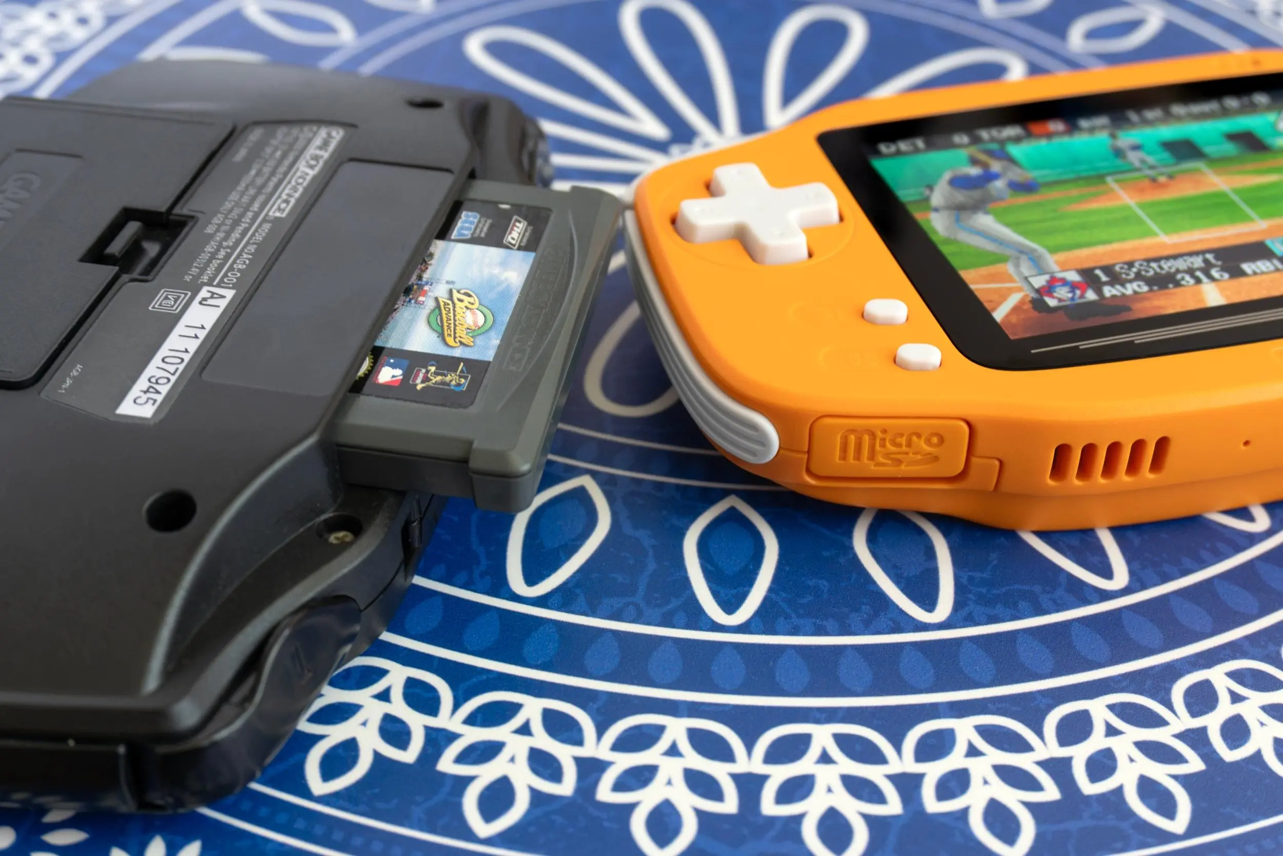 The Ayaneo Konkr Pocket Advance next to an upgraded Game Boy Advance with a game cartridge half inserted.