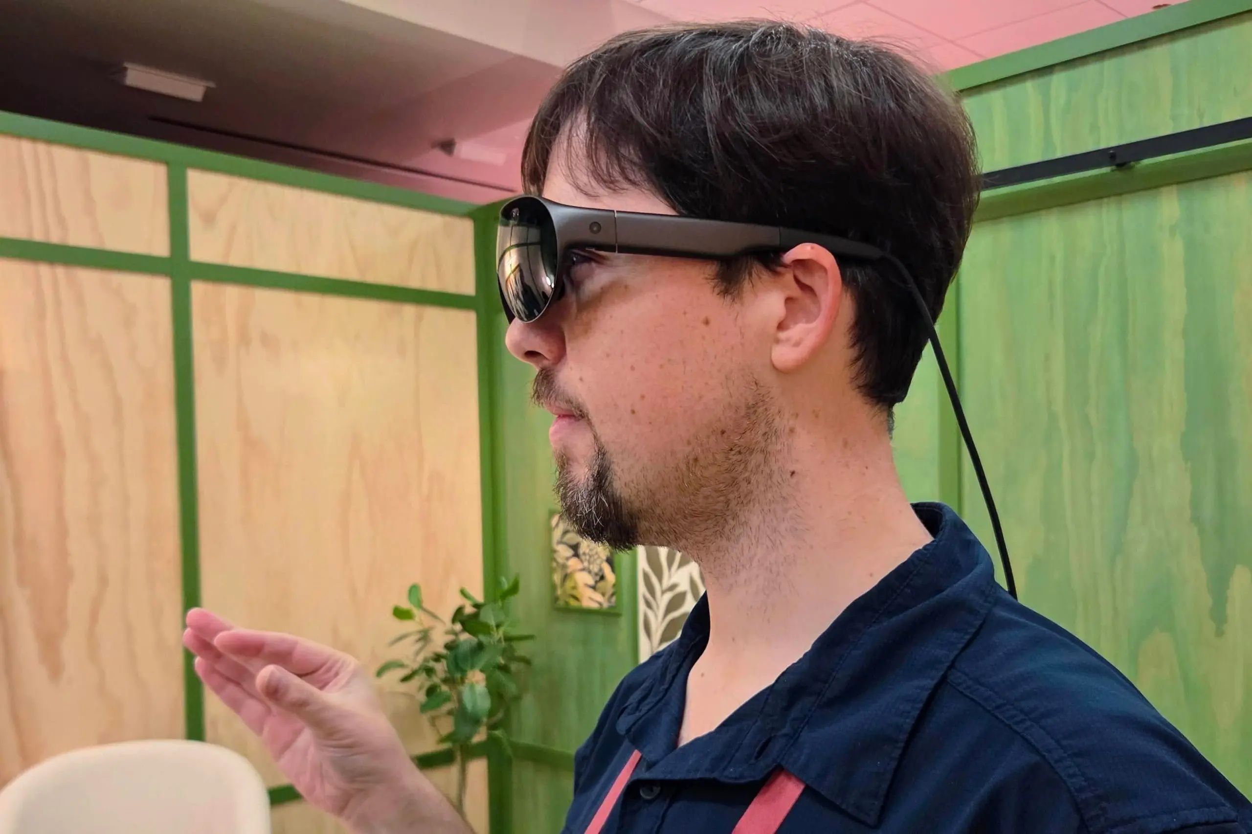 Sean Hollister wears Meta’s VR Glasses in profile, a cable dangling down the back of his head.