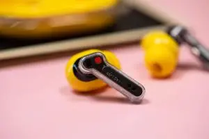 The Nothing Ear 3A earbuds on a mauve background with their case.