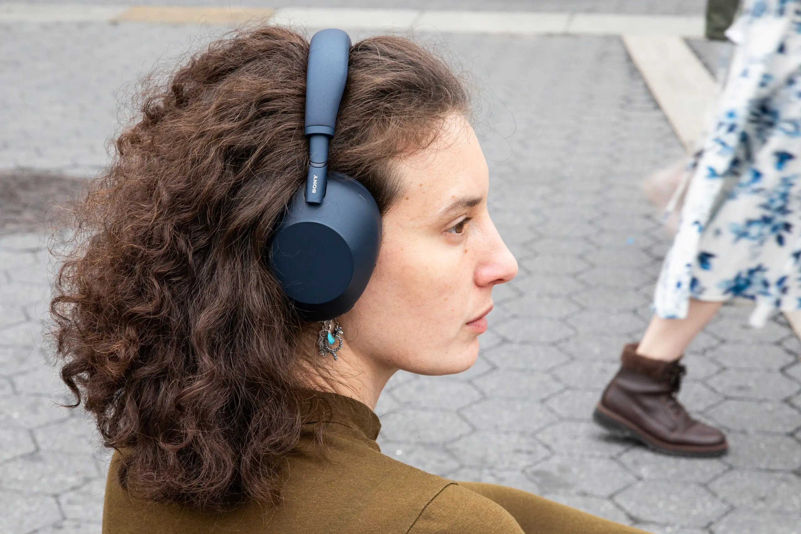 Woman with long curly hair wearing a set of over-the-ear headphones.