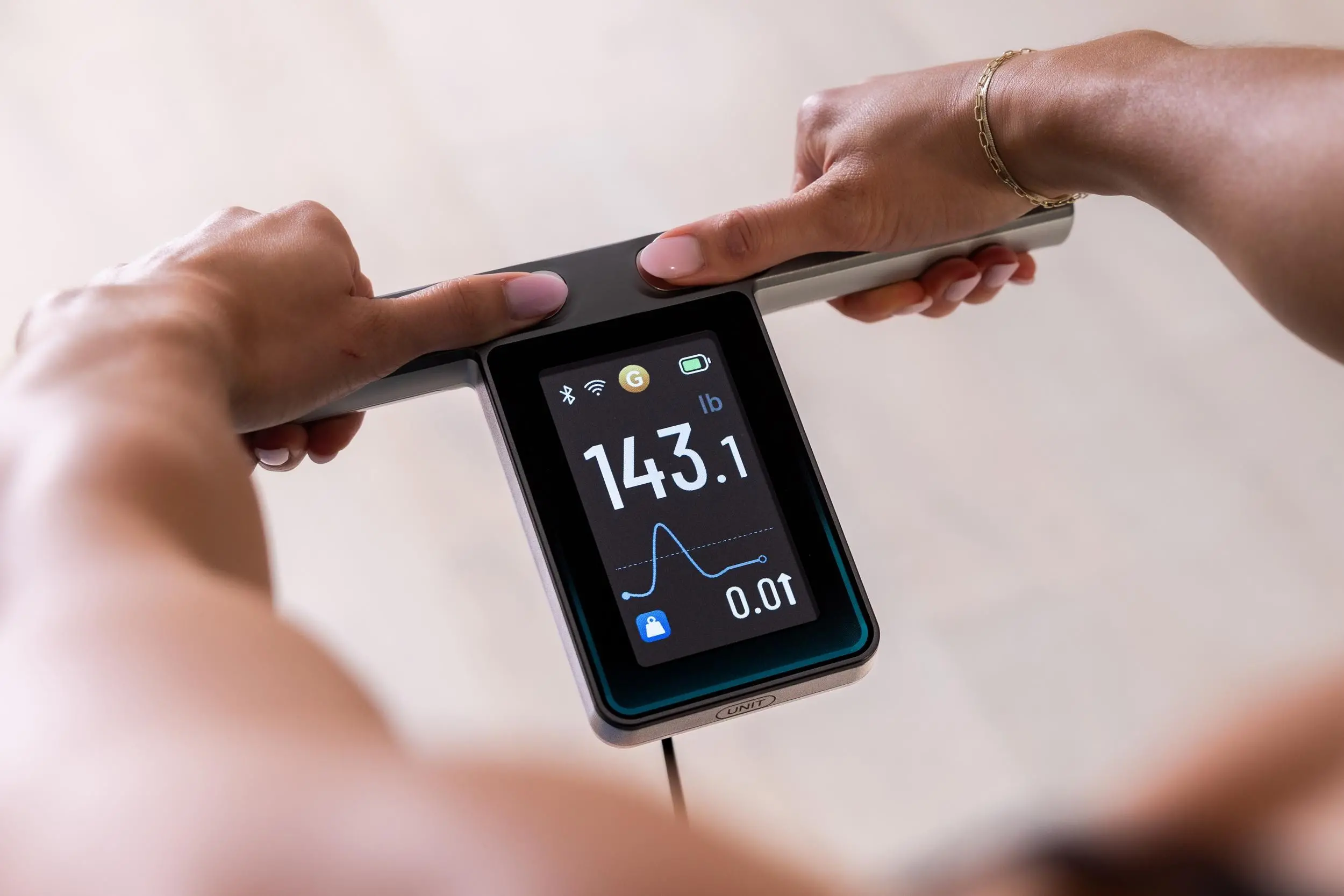 A person holds the screen-equipped handle on the Wyze Scale Ultra BodyScan Plus.