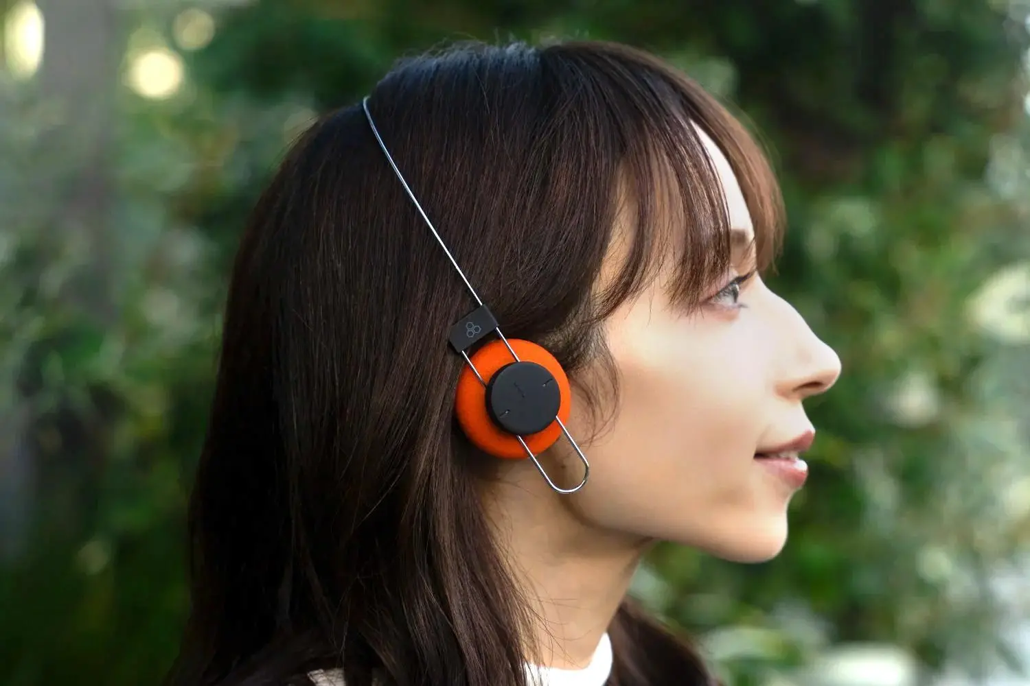 A person wears the Final Porta wireless headphones with orange ear pads.