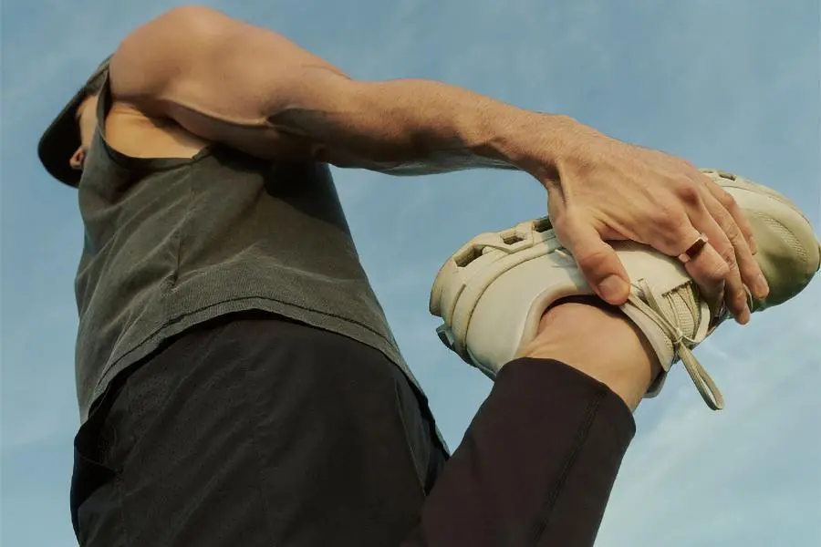 A person stretches their leg by holding their foot while wearing an Oura smart ring.