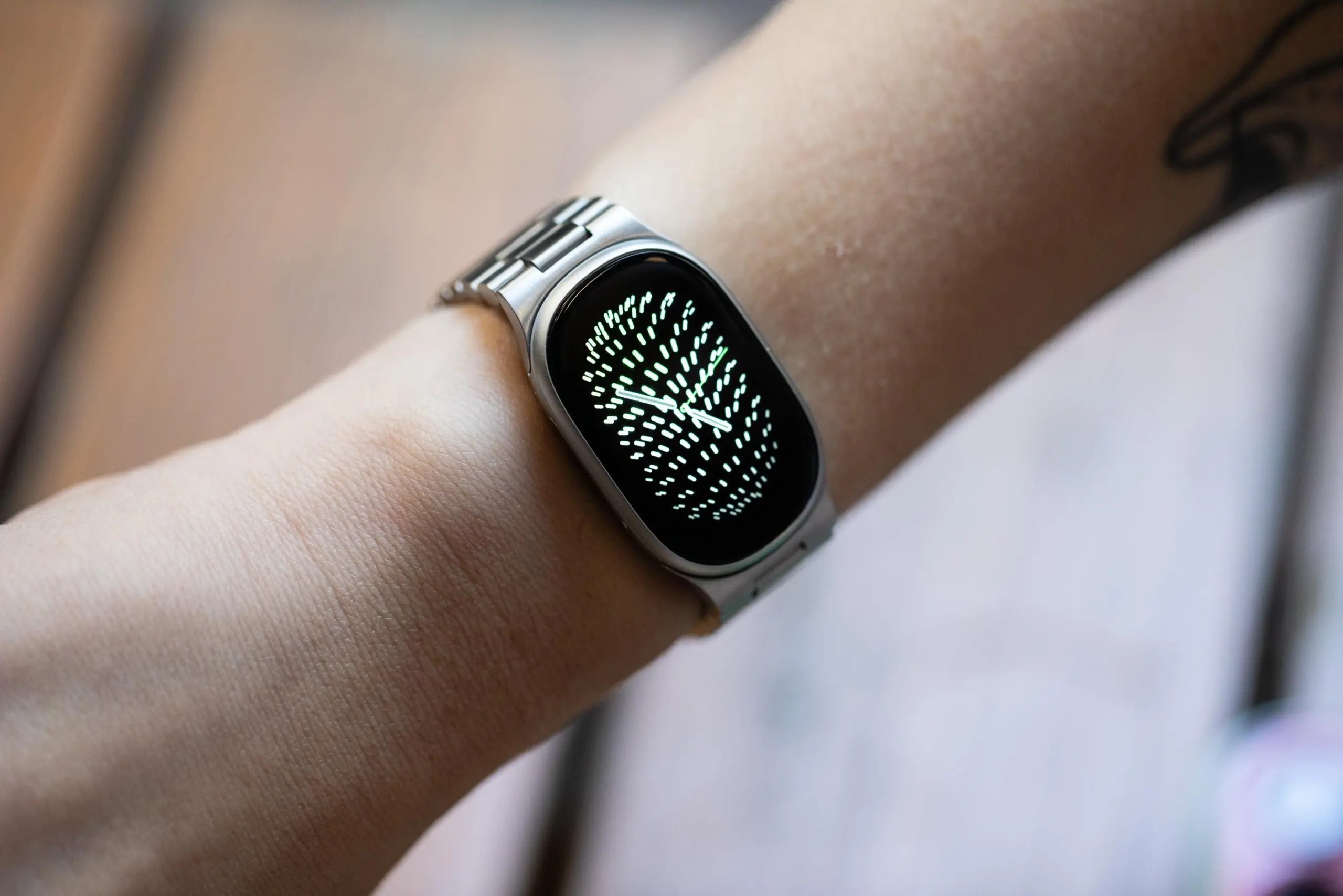 Close up of the Fitbit Edge on a person’s wrist with the new metal links bracelet and a watchface that shows noticeable black bezels around the edge.