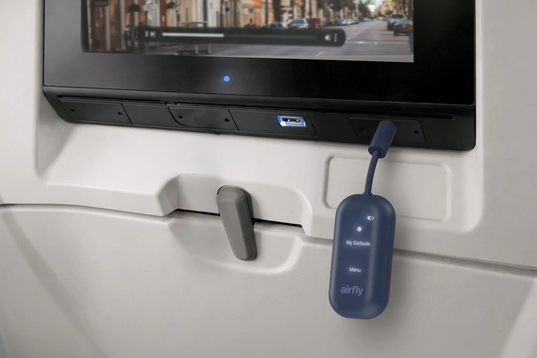 The Twelve South Airfly View wireless dongle is connected to the headphone jack on an in-flight entertainment system.
