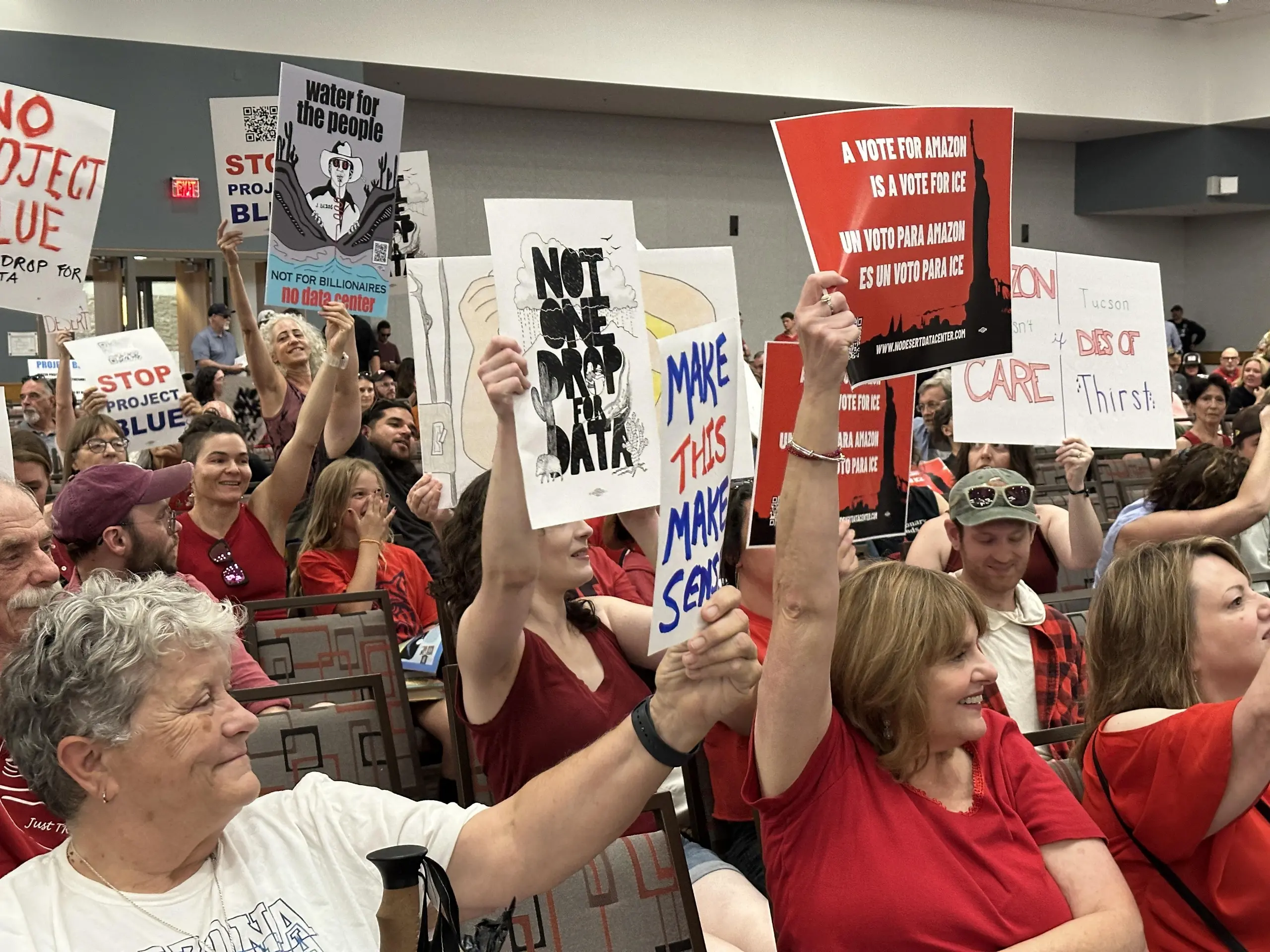 Crowd of people wearing red shirts holding signs that read "Not one drop for data centers".