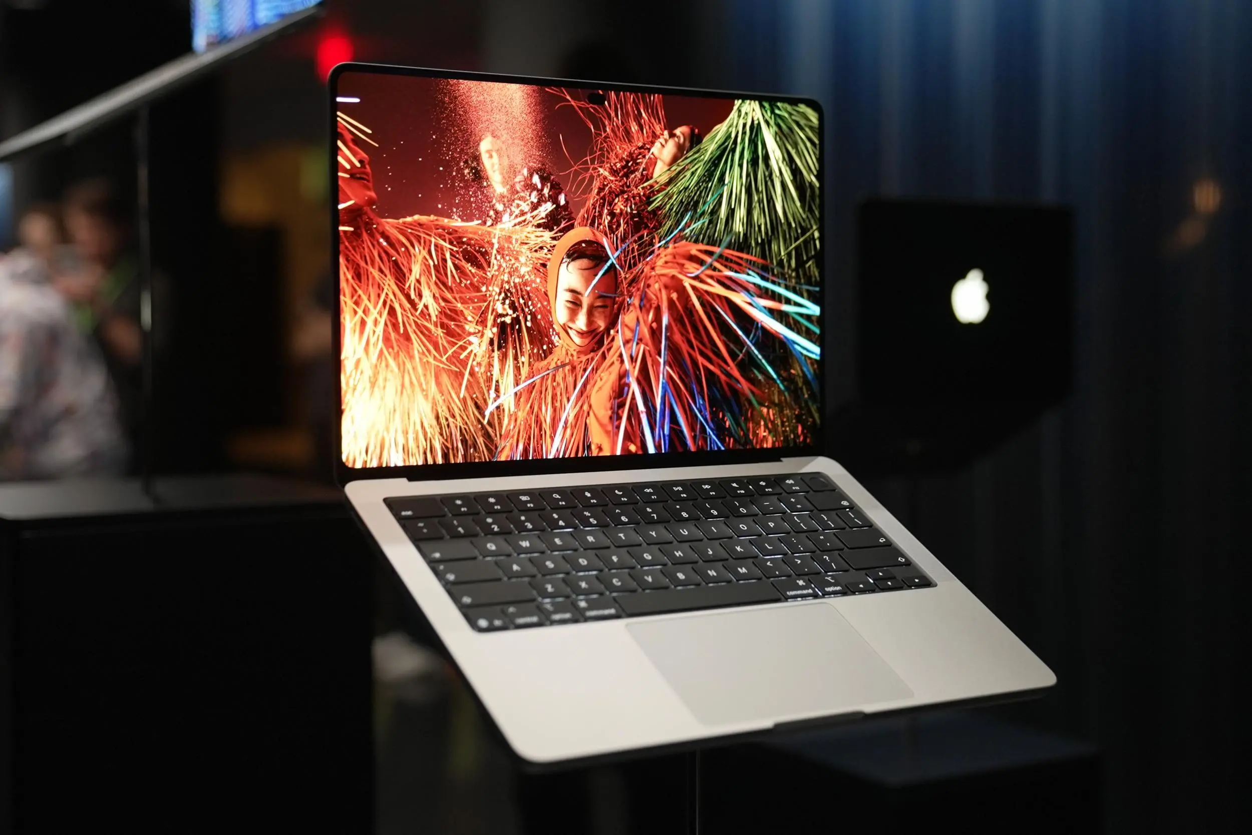 The new Apple touchscreen MacBook pro laptop on a display stand surrounded by other laptops.