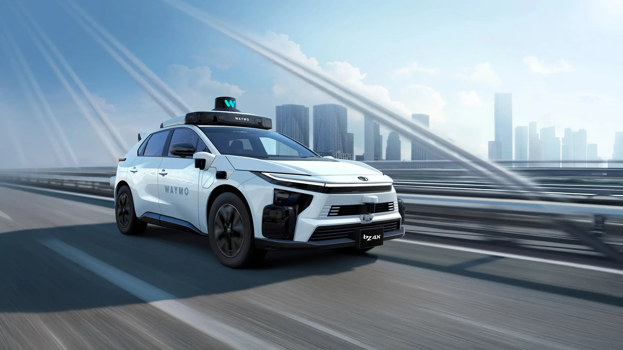 A front-angle view of a Waymo Toyota bZ4x with a city skyline in the background.